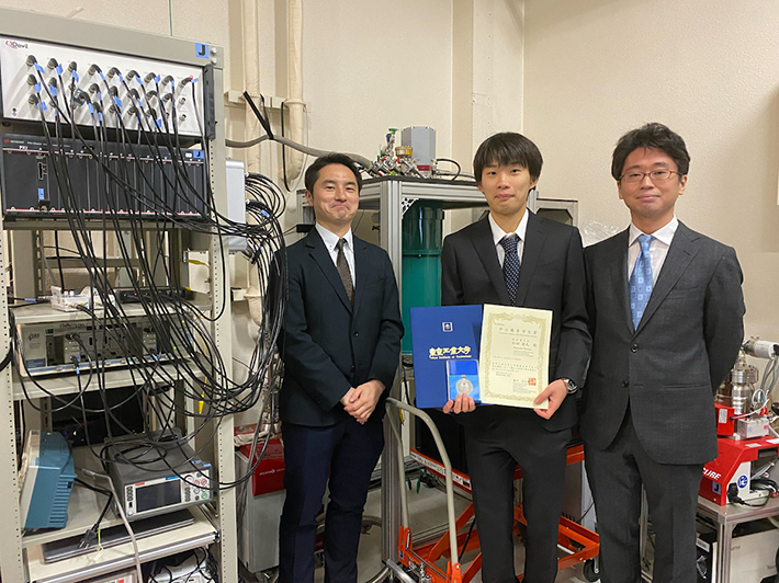小寺 哲夫准教授（左）、松田 達也さん（中央）、米田 淳特任准教授（右）奥は研究に用いた冷凍機、左は測定機器。