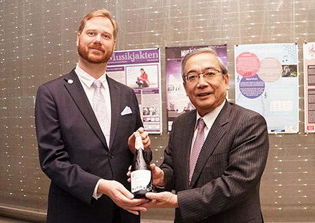 Mishima presenting bottle of sake to Nobel Museum