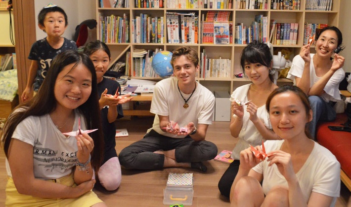 きれいに出来上がった折り鶴を見せ合う留学生と山川さん（右から3人目）
