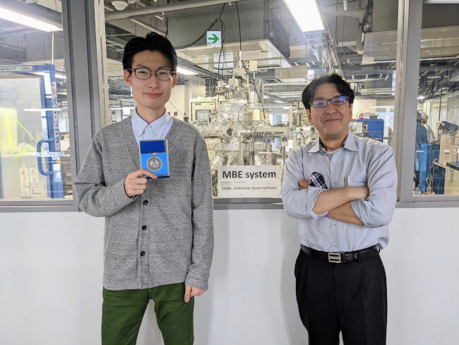 福田遼太郎さん（右）と山田明教授（左）。奥は太陽電池製膜装置。