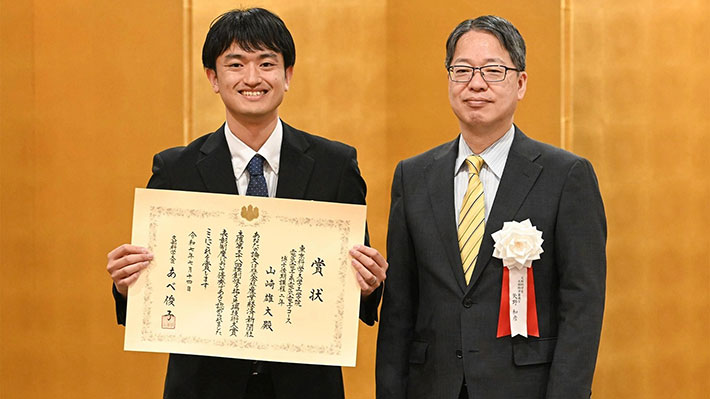 授賞式で賞状を授与された山崎雄大さん（左）と文部科学省の矢野和彦文部科学審議官