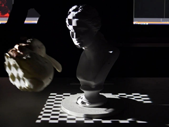 Comparison of projection mapping results using a single projector and a multi-projector system - A single projector cannot eliminate the shadow caused by the moving object at the left on the projection target placed in the center.