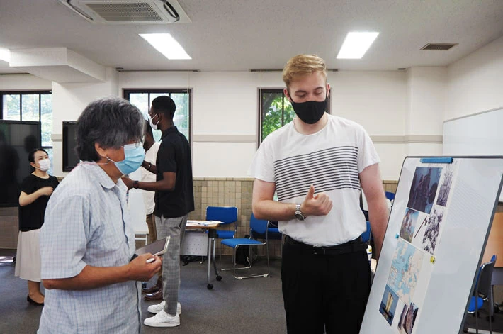 Course participant (right) explaining poster to ILA Prof. Yamamoto