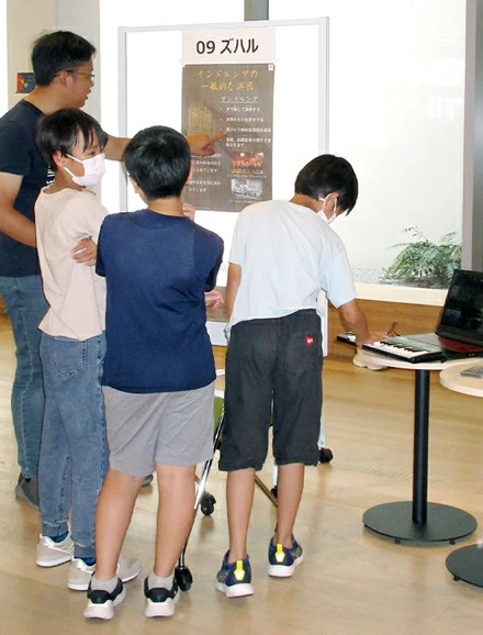 Children using computer to play traditional Indonesian instrument