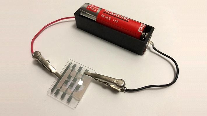 図1．乾電池（1.5 V）1本で白色有機ELを光らせている写真