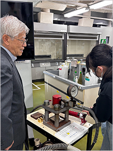 Sakurai (left) supervising student during pressure-molding process