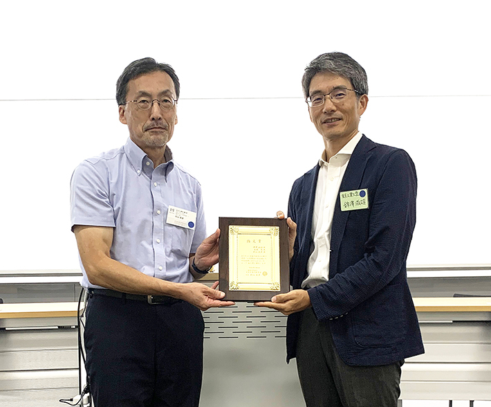 Professor Murayama (left) and Associate Professor Nishizawa (right) received the plaques at the awards ceremony of the annual meeting.