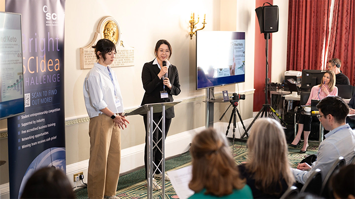 決勝大会でプレゼンテーションする小島さんとヘイムスさん（藤倉さんはオンラインで参加）